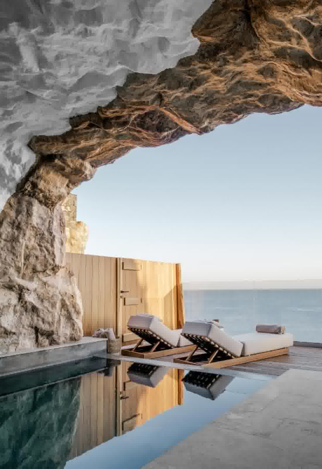 Terrasse privée sous une voûte de pierre, bains de soleil et piscine à débordement face à la mer
